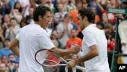 Sergiy Stakhovsky (kiri) menyalami Roger Federer sesudah mengalahkannya dalam putaran kedua (26/6). Kemenangannya yang mengejutkan itu tidak bertahan lama karena Stakhovsky akhirnya tersungkur di tangan Jurgen Melzer dalam putaran selanjutnya.