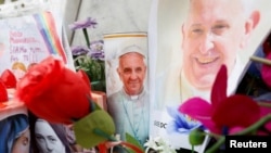 Decorated candles, flowers and pictures of Pope Francis are placed at the base of the statue of the late Pope John Paul II outside Gemelli Hospital, where Pope Francis is admitted for treatment, in Rome, Italy, Feb. 24, 2025.