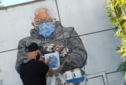 FILE - Artist Jonas Never paints a mural of Senator Bernie Sanders, in Culver City, California, Jan. 24, 2021.