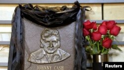 Plakat kuningan hall of fame untuk menghormati penyanyi musik country Johnny Cash terbungkus hitam dengan mawar merah di samping di County Music Hall of Fame and Museum di Nashville, Tennessee, 12 September 2003. (Foto: Reuters)