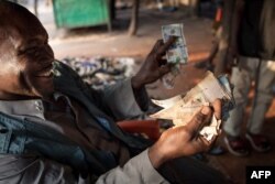 FILE - A merchant in the Central African Republic shows Sudanese bank bills, Dec. 20, 2017.