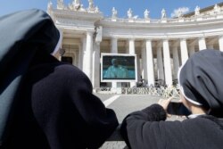 Nuns watch Pope Francis on a giant screen as he delivers the Angelus, in St. Peter's Square, at the Vatican, March 8, 2020.