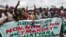 Les gens applaudissent derrière une banderole "Adjame dit non, non et non, à un 3e mandat de Ouattara", le 26 septembre 2020, à Yopougon, Abidjan.