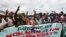 Les gens applaudissent derrière une banderole "Adjame dit non, non et non, à un 3e mandat de Ouattara", le 26 septembre 2020, à Yopougon, Abidjan.