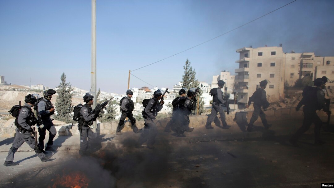 Polisi perbatasan Israel berlari dekat ban yang dibakar dalam bentrokan dengan warga Palestina karena insiden pada hari Rabu di Issawiya, Yerusalem timur, 24 Oktober 2014.