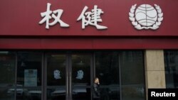 FILE - A man walks outside a branch of traditional Chinese medicine firm Quanjian Group in Hangzhou, Zhejiang province, China, Dec. 27, 2018.