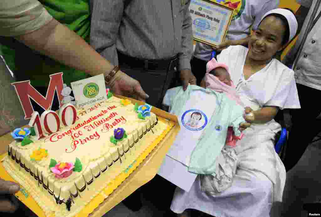 Dailin Duras Cabigayan, 27, smiles as she cradles her newly born baby girl, Chonalyn, as government health officials present her with a cake and clothing as the 100 millionth baby born into the Philippines&#39; population during a short ceremony inside the Jose Fabella hospital in Manila.