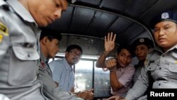 Detained Reuters journalists Wa Lone and Kyaw Soe Oo sit beside police officers as they leave court in Yangon, Myanmar, July 9, 2018. The two were charged with breaching the colonial-era Official Secrets Act.