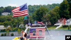 A jet skier passes a patriotic shanty-boat owned by AJ Crea on Pontoosuc Lake on Labor Day in Pittsfield, Mass., Sept. 7, 2020.