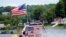 A jet skier passes a patriotic shanty-boat owned by AJ Crea on Pontoosuc Lake on Labor Day in Pittsfield, Mass., Sept. 7, 2020.