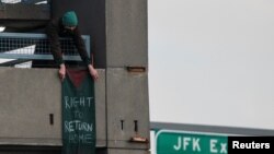 A pro-Palestinian demonstrator places a banner at the parking lot of Terminal 4 as security units await the arrival of an expected protest at the JFK International Airport in New York, Jan. 1, 2024. 
