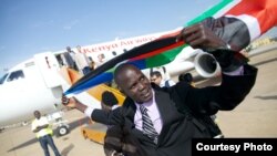 Olympic athlete and former refugee Guor Marial raises the flag of South Sudan after returning to the country. 