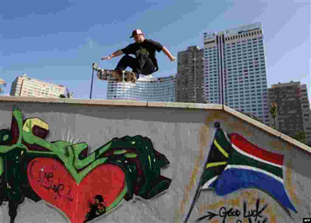 A skateboarder jumps at Durban beach as graffiti of the South African flag in support of the country's national soccer team is painted on the wall, Monday, June 14, 2010. (AP Photo/Thanassis Stavrakis)