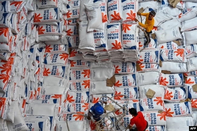 Pekerja membongkar karung beras yang diimpor dari Thailand oleh Perum Bulog di pelabuhan Malahayati, Provinsi Aceh, 1 Maret 2024. (CHAIDEER MAHYUDDIN/AFP)