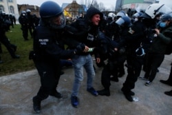 Police officers remove demonstrators from a square during a protest against the government's COVID-19 restrictions in Kassel, Germany, March 20, 2021.