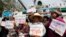 Farmers hold signs in front of a combine harvester during a rally demanding the Yingluck administration resolve delays in payment from the rice pledging scheme outside the Commerce Ministry in Nonthaburi province, on the outskirts of Bangkok, Feb. 6, 2014