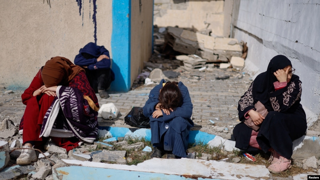 Personas descansan junto a edificios dañados mientras palestinos llegan a Rafah después de ser evacuados del Hospital Nasser en Khan Younis debido a la ofensiva terrestre israelí contra Hamas, en el sur de la Franja de Gaza, el 15 de febrero de 2024.