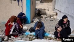 FILE—People rest next to damaged buildings, as Palestinian arrive in Rafah after they were evacuated from Nasser hospital in Khan Younis due to the Israeli ground operation, amid the ongoing conflict between Israel and Hamas, in the southern Gaza Strip, February 15, 2024.