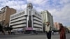 FILE - A man and a woman walk past the Rebiya Kadeer Trade Center, center, on Sept. 6, 2009, in Urumqi, in China's western Xinjiang region. The building, once once a vibrant hub for more than 800 mostly Uyghur-owned businesses, was recently demolished.