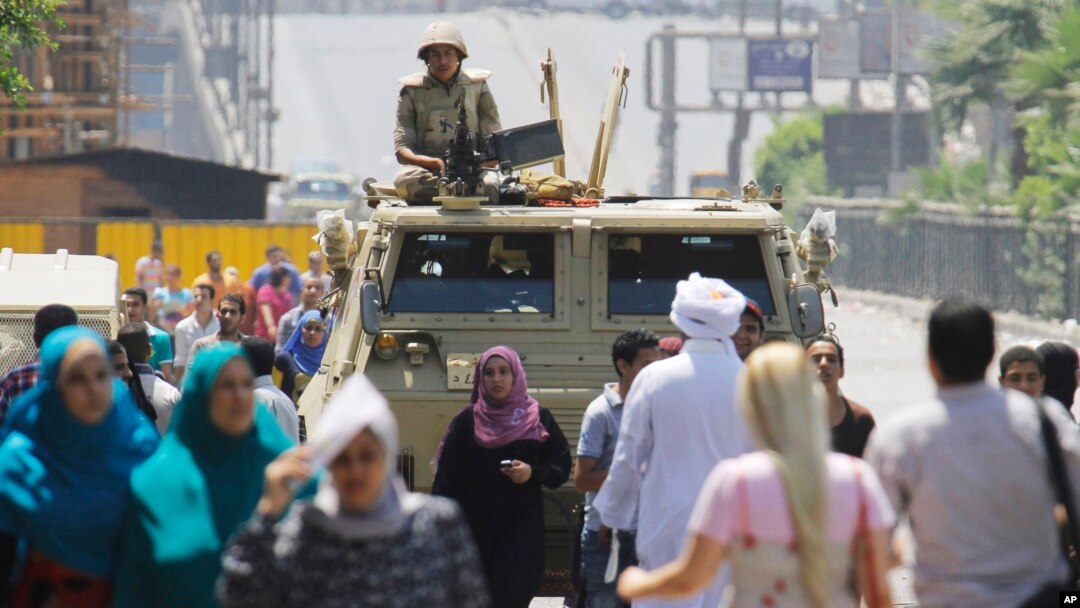 Seorang tentara Mesir berjaga dengan kendaraan lapis baja dekat lapangan Nahda, tempat para pendukung Presiden terguling Mohammad Morsi berkemah di sekitar Universitas Kairo, Giza (12/8).