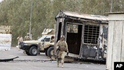 Iraqi Army soldiers stand guard near burned trailers at Camp Ashraf north of Baghdad, Iraq, April 8, 2011 (file photo).