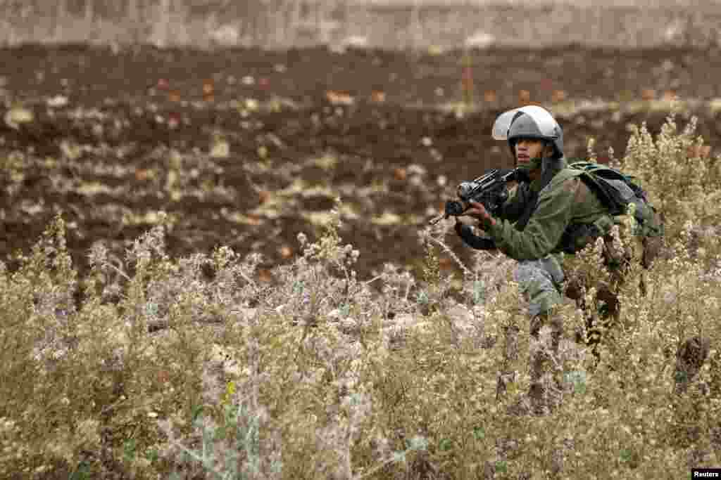 An Israeli soldier takes position during clashes with Palestinian stone-throwers outside Ofer prison near the West Bank city of Ramallah November 18, 2012. The clashes broke out following a protest against Israel's military operation in the Gaza Strip. RE