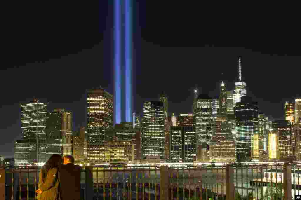 A couple embraces on the Brooklyn Promenade as the Tribute in Light rises above the lower Manhattan skyline in New York, Sept. 10, 2017.