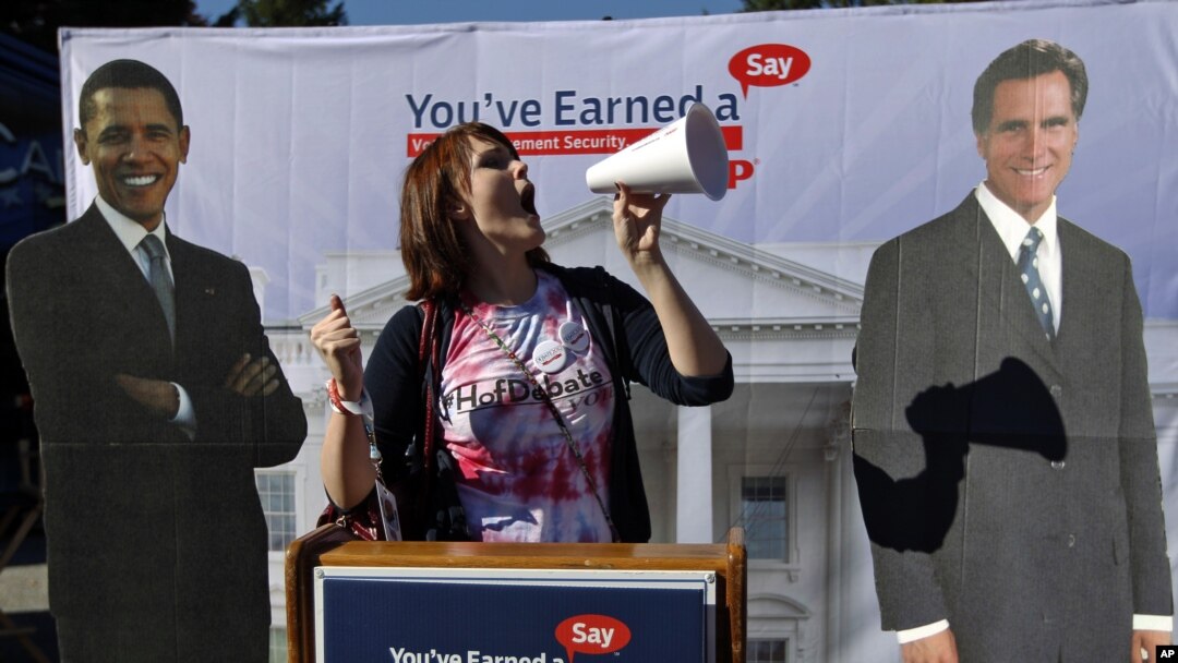 Hofstra University junior Corinne Mestemacher poses with cardboard cut outs of President Barack Obama and Republican presidential candidate Mitt Romney ahead of the presidential debate, Hempstead, New York, October 16, 2012.
