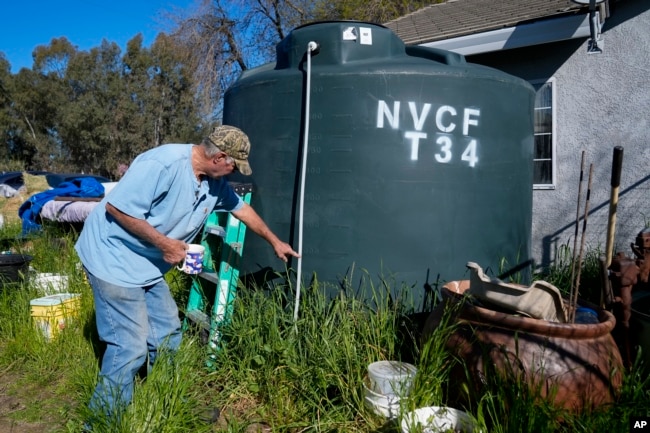 Fred Imfeld points to the level on his water tank Sunday, March 17, 2024, in Corning, Calif. They also get potable water delivered as the couple tries to save to drill a new well. (AP Photo/Godofredo A. Vásquez)