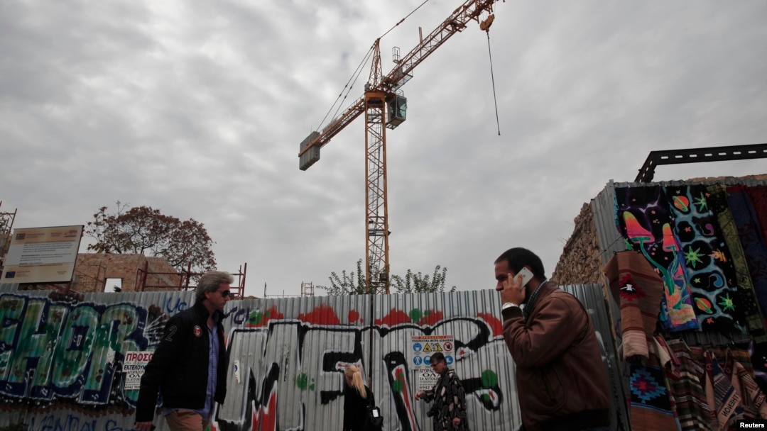 FILE - People walk past a construction yard in Athens, Nov. 7, 2014. 