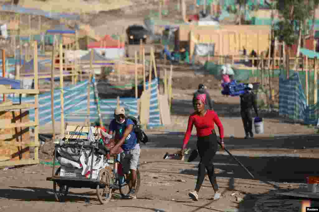 Personas trasladan sus pertenencias durante el desalojo de un asentamiento no autorizado sin agua potable, alcantarillado y electricidad, donde muchos se han mudado con sus familias durante la pandemia, en las afueras de Santiago, Chile.