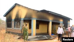 FILE - Security officers and residents assess the damage at Arabia Boys Secondary School after suspected al-Shabaab militants threw an explosive device at a teacher's house in Mandera county, Kenya, Oct. 10, 2018. 