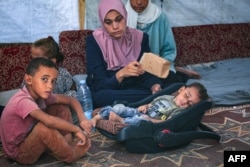 Palestinian boy Abdel Rahman Abu al-Jedian, who contracted polio a month ago, sleeps surrounded by family members in their displacement tent in Deir al-Balah in the Gaza Strip on Aug. 27, 2024.