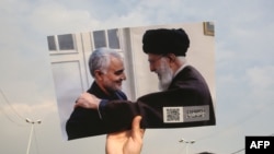 A man holds a picture of Iran's supreme leader Ayatollah Ali Khamenei with Iranian Revolutionary Guards top commander Qasem Soleimani during a demonstration in Tehran, Jan. 3, 2020, against the killing of Soleimani in a U.S. strike in Baghdad.