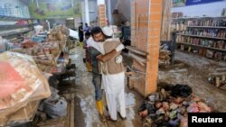 FILE - Two men embrace inside a damaged grocery store affected by fatal floods, in Derna, Libya, September 28, 2023.