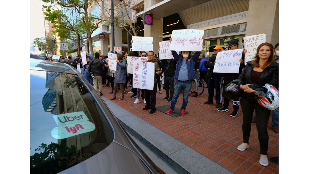 FILE - Uber and Lyft drivers demonstrate outside of Uber headquarters, May 8, 2019, in San Francisco.