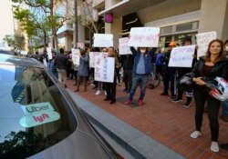 FILE - Uber and Lyft drivers demonstrate outside of Uber headquarters, May 8, 2019, in San Francisco.