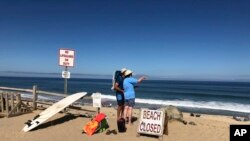 Dua orang mengamati laut setelah ada laporan tentang serangan ikan hiu di Newcomb Hollow Beach, Wellfleet, 15 September 2018.