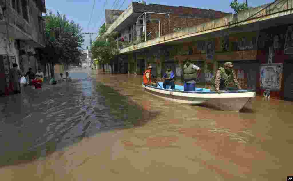 A Pakistani army soldier and volunteers use a boat in floodwater to rescue people after heavy monsoon rains in Wazirabad, north of Lahore, Sept. 7, 2014.