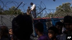 Hungarian police and army officers oversee the distribution of food as people queue at a camp in Horgos, Serbia, on Serbia's border with Hungary, July 11, 2016. 