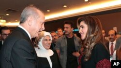 Turkey's President Recep Tayyip Erdogan, left, accompanied by his wife Emine, center, shakes hands with Jordan's Queen Rania, at a conference in Istanbul, Oct. 4, 2018.