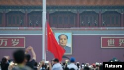 Visitors watch a flag-raising ceremony as the sun rises at Tiananmen Square