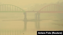 A resident rides a motorcycle on the haze-shrouded Betrix bridge in Sarolangun, on Indonesia's Jambi province, Oct. 7, 2015.