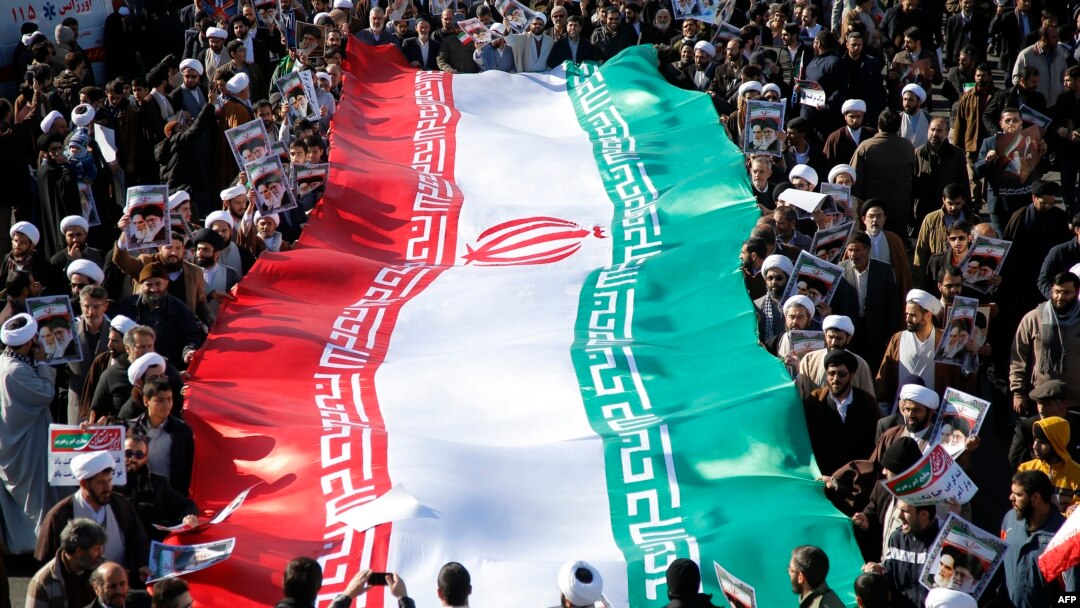 Demonstran pro-pemerintah melambaikan bendera nasional mereka dalam aksi unjuk rasa di kota suci Iran, Qom, sekitar 130 kilometer selatan Teheran, 3 Januari 2018.