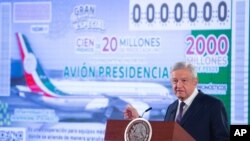 Presiden Andres Manuel Lopez Obrador berdiri di depan gambar tiket undian yang menampilkan pesawat kepresidenan, dalam konferensi pers pagi di Istana Nasional di Meksiko. (Foto: Kantor Pers Presiden Meksiko via AP) 