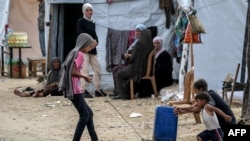 Anak-anak pengungsi Palestina sedang mendorong jeriken air di kamp penampungan di Rafah, bagian selatan Jalur Gaza, 30 April 2024 di tengah konflik antara Israel dan kelompok militan Hamas Palestina. (Foto: AFP)