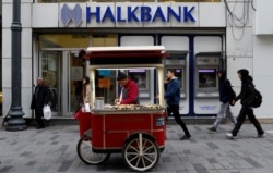 A street vendor sells roasted chestnuts in front of a branch of Halkbank in central Istanbul, Turkey, Jan. 10, 2018.