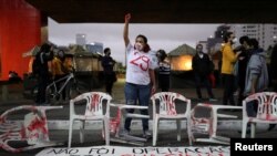 A woman raises her fist as Black movement activists protest in Sao Paulo against police violence after a deadly police operation in Rio de Janeiro's Jacarezinho slum, in Brazil, May 8, 2021. The banner reads: 'It was not an operation, it was a massacre'.