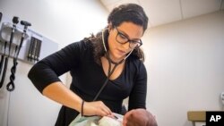 FILE - Dr. Jasmine Saavedra, whose parents emigrated from Mexico in the 1980s, examines a newborn in Chicago, Aug. 13, 2019. Public health experts have warned against efforts to deny green cards to immigrants who use public assistance.