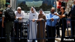 Palestinians stand next to a police barricade as they wait for the compound known to Muslims as Noble Sanctuary and to Jews as Temple Mount to be reopened, in Jerusalem's Old City, July 16, 2017.